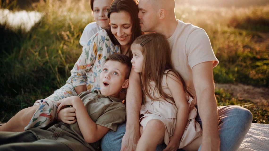 A joyful family enjoying quality time together on a sunset-lit meadow.