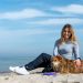 Woman enjoying a sunny day on Kołobrzeg beach with her dog, capturing the essence of leisure and companionship.